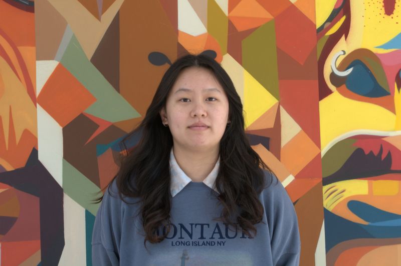 Portrait of Tutor Erica, smiling in front of colorful mural