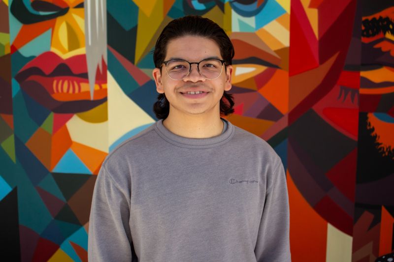 Portrait of tutor Vincent smiling in front of colorful mural