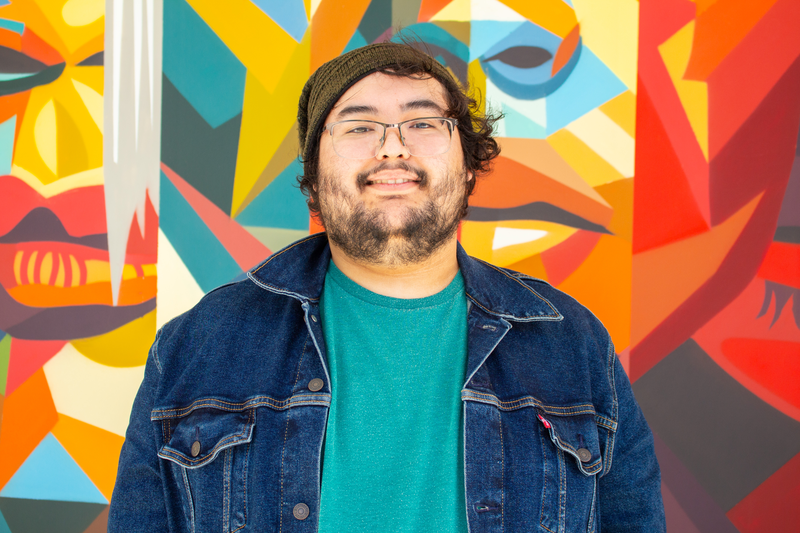 Portrait of tutor Nathan Vincent smiling in front of colorful mural
