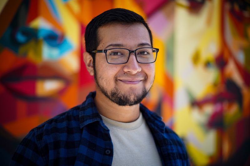 Portrait of tutor Ketzalt smiling in front of colorful mural