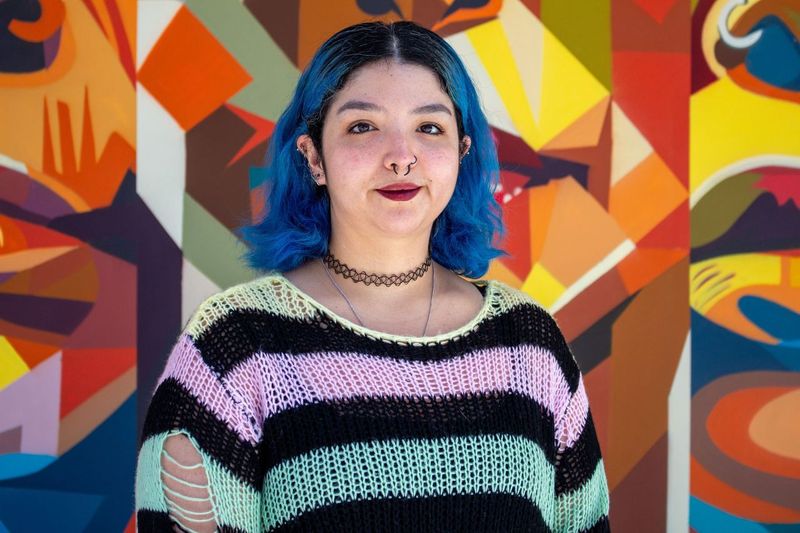 Portrait of tutor Gizelle smiling in front of colorful mural