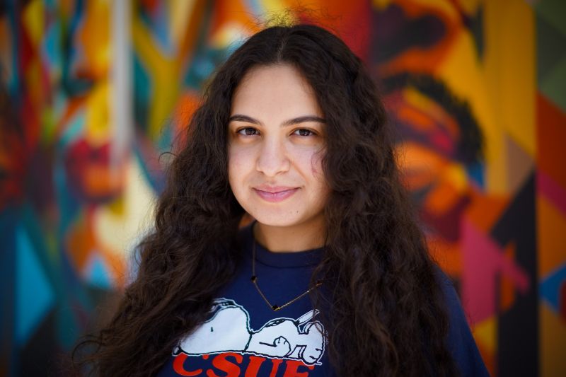 Portrait of tutor Layal smiling in front of colorful mural