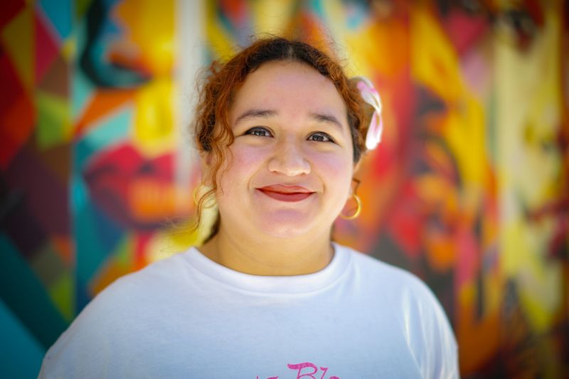 Portrait of tutor Val smiling in front of colorful mural