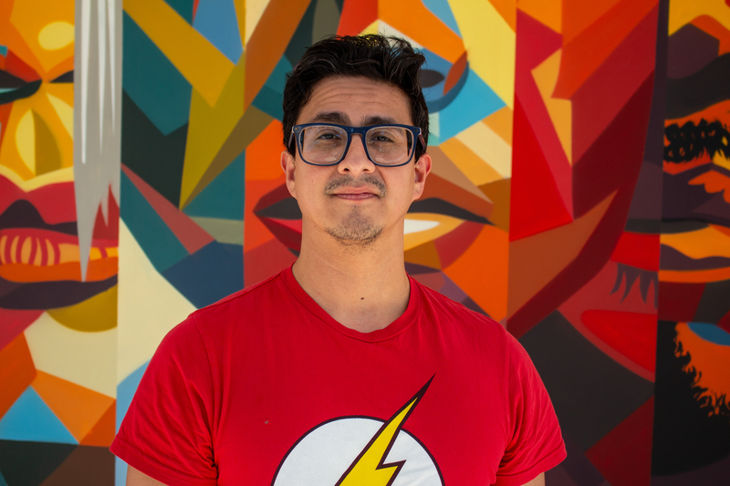 Portrait of tutor Angel smiling in front of colorful mural