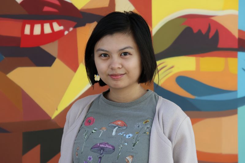 Portrait of tutor Samantha "Wild" smiling in front of colorful mural