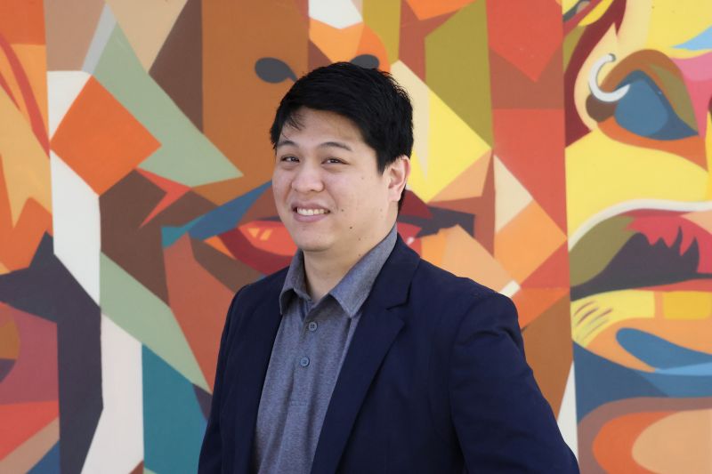 Portrait of tutor Jeffrey smiling in front of colorful mural