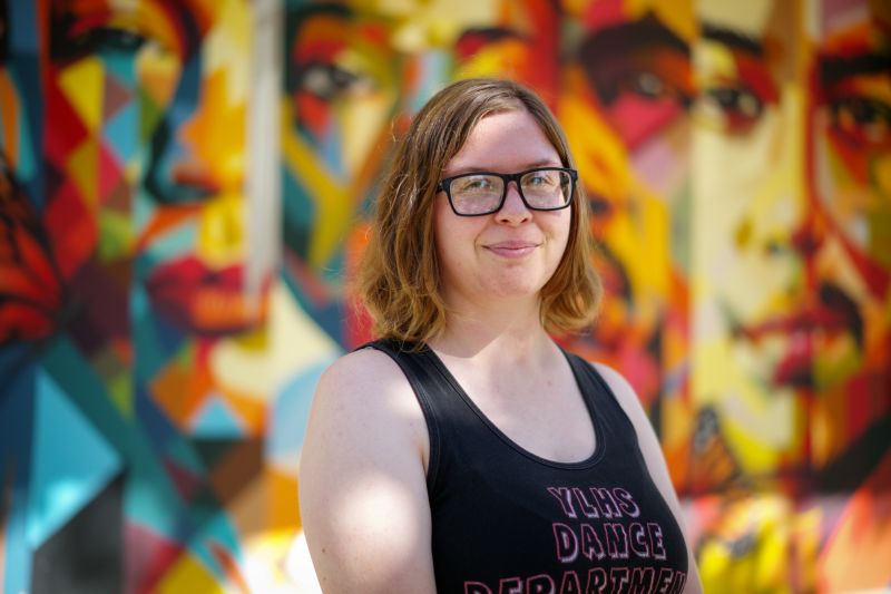 Portrait of tutor Megan smiling in front of colorful mural