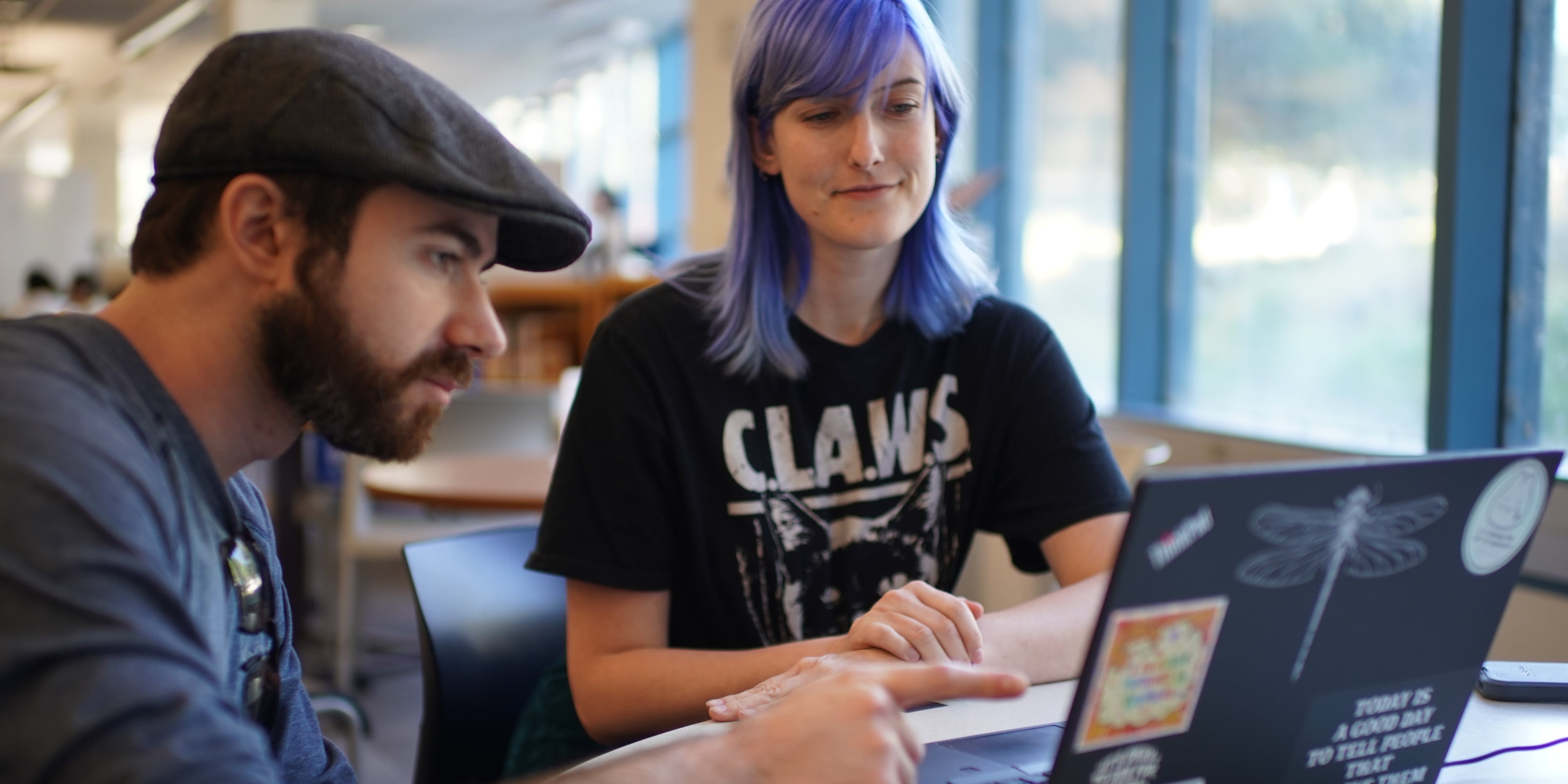 Male and female tutor and student work on a laptop at a desk