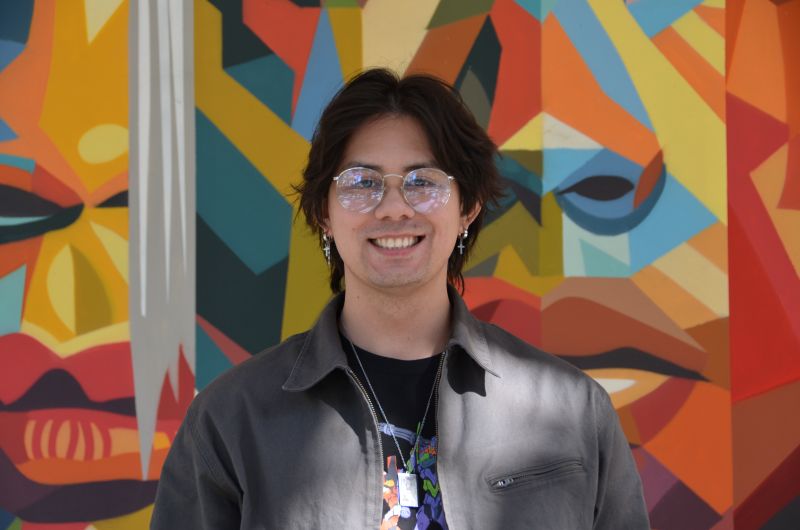 Portrait of tutor Brandon smiling in front of colorful mural